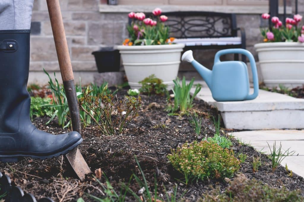 femme en bottes de caoutchouc creuse un trou pour planter une oya