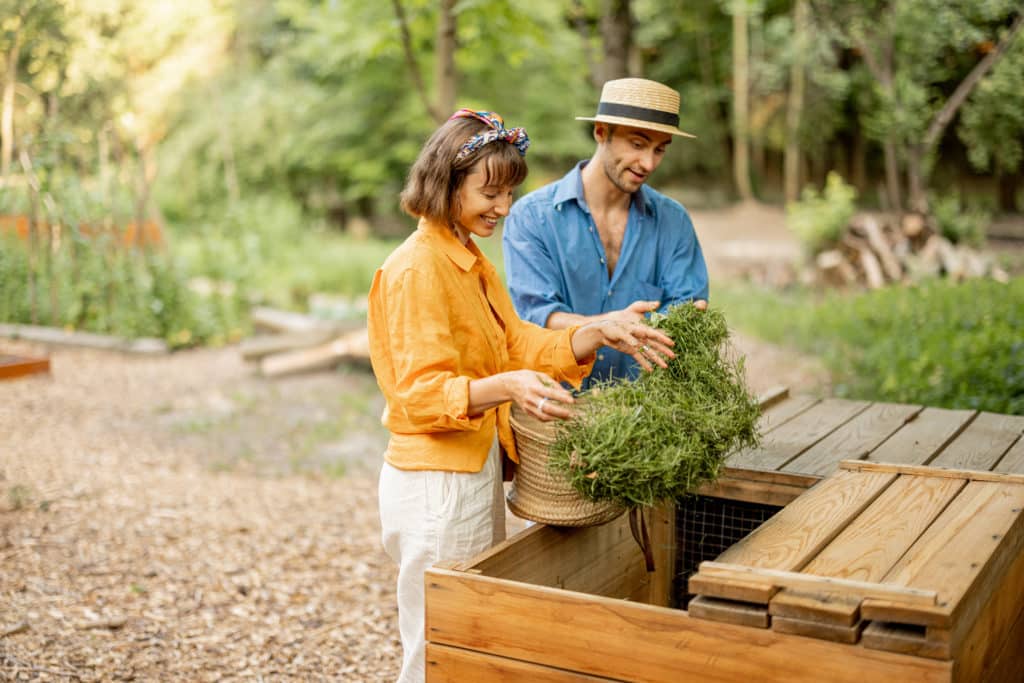 Couple utilisant un compost en bois pour un jardinage écologique